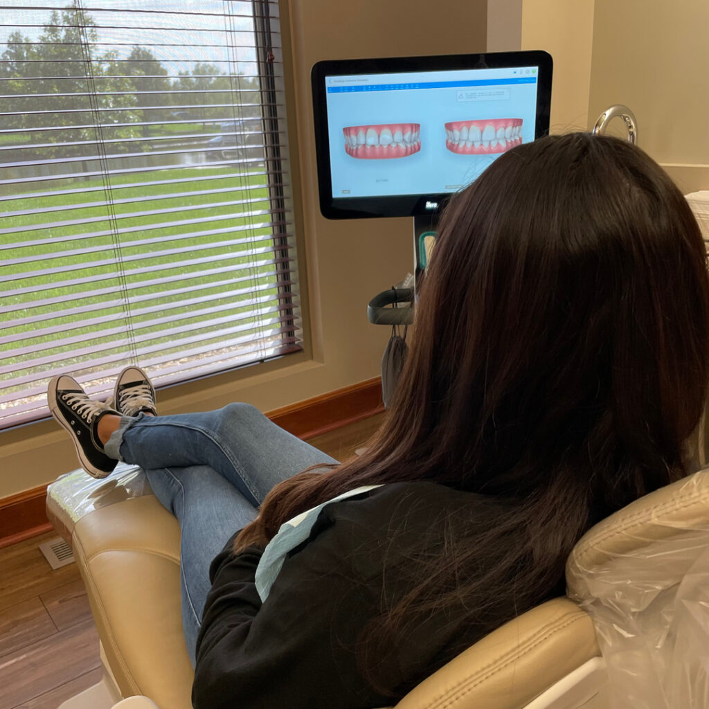 Female patient examining model of teeth on digital display in exam room at Derby Dental Care, engaging in her treatment plan.