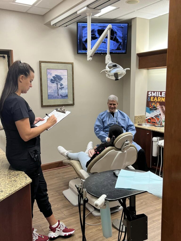 Dr. Pierson discussing dental information with a hygienist taking notes at Derby Dental Care, highlighting teamwork.