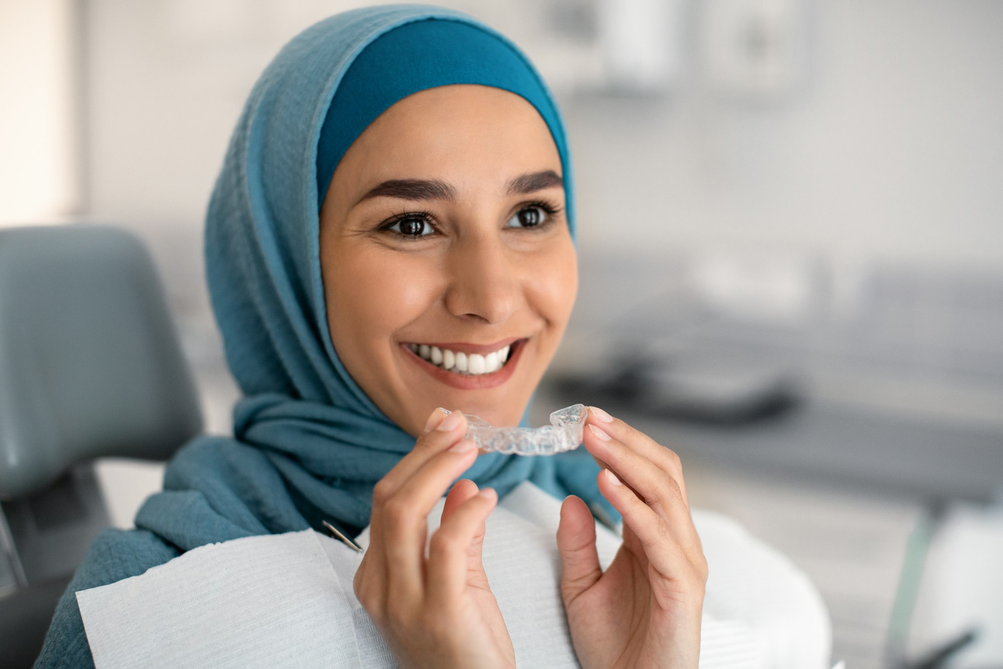 Woman inserting Invisalign aligner in mouth, on Invisalign Information page at Derby Dental Care.